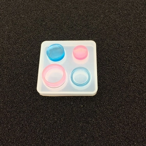 Macro detail of square silicone mold showing four round cavities and resin casting results