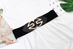 Close-up of black elastic wide belt with golden interlocking buckle on white dress