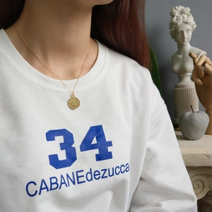Close-up of a 925 sterling silver golden coin pendant necklace worn by a model