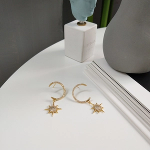 Detail of gold star and moon drop earrings displayed on a clean white surface