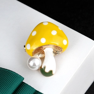 Macro detail of cute yellow mushroom brooch with white polka dots and a large pearl bead