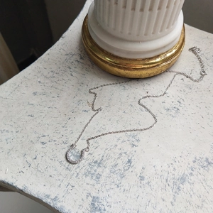 Macro detail of silver horseshoe pendant with micro-inlaid zircons on a delicate chain