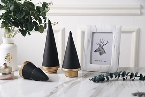 Detail of three matte black and gold ceramic Christmas tree ornaments on marble