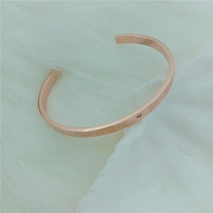 Detail of rose gold C-shaped cuff bracelet with Forever Love engraving and small diamond