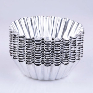 Stack of silver aluminum baking molds with classic fluted edges on purple background
