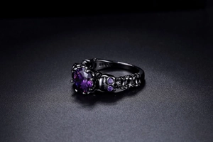 Macro detail of gothic skull ring with large purple zircon and black metal finish