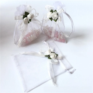 Detailed view of white organza gift bags featuring rose flower drawstring and faux pearls