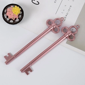 Pink vintage key-shaped gel ink pens with metallic finish on a white decorative setting