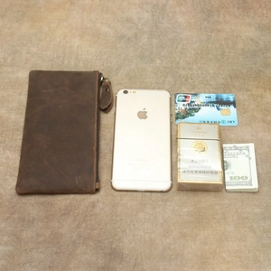 Detail view of crazy horse leather wallet with phone and cards on brown fabric