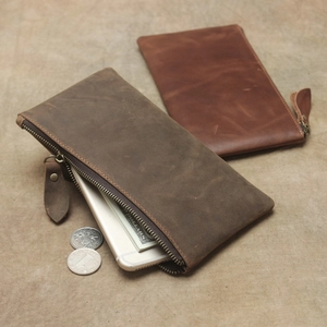 Macro view of two brown crazy horse leather wallets with vintage brass zipper detail