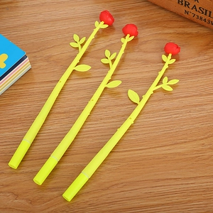 Three creative yellow and green rose flower pens on a rustic wooden desk surface