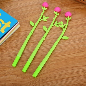 Three creative pink rose floral gel pens with green stems on a rustic wooden desk