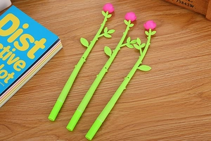 Detailed view of three pink rose shaped pens with green stems on a rustic wooden background