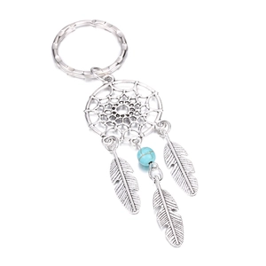 Macro detail of silver dreamcatcher keychain with blue bead and hanging metal feathers