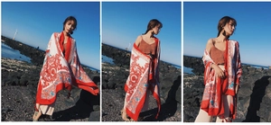 Bohemian red and white printed long scarf draped over shoulders on beach rocks