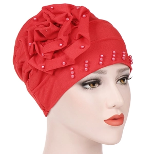 Detailed view of red fabric turban cap with 3D floral accent and pink pearl beads