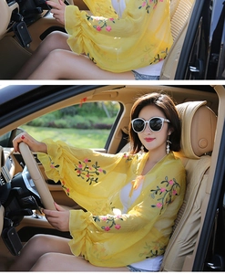 Detail of yellow chiffon sun protection shawl with pink floral embroidery and ruffled cuffs