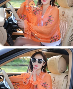 Detail of orange floral embroidered chiffon sun protection shawl worn inside a vehicle