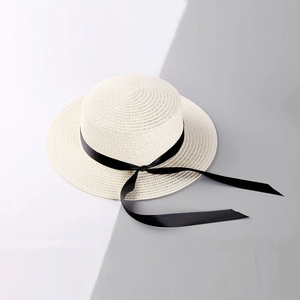 Close-up of the woven straw texture and elegant black silk ribbon on a beige boater hat