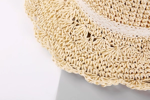 Vue détaillée du chapeau de paille tissé avec une bordure délicate en dentelle blanche