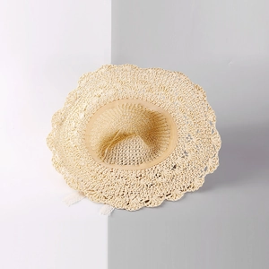 Détail du chapeau de paille tissé avec bords ondulés et rubans en dentelle blanche