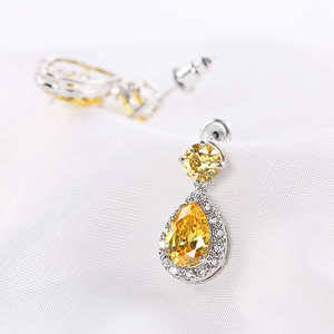 Macro shot of silver drop earrings featuring bright yellow teardrop cubic zirconia stones