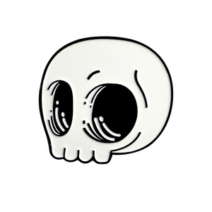 Detailed close-up of a skull-shaped enamel pin with white and black finish for Halloween