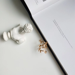 Detail of gold leaf wrap ring on white desk with aesthetic David bust and open book