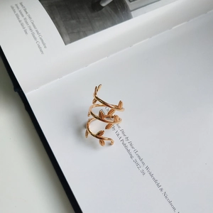 Detailed view of golden leaf spiral wrap ring on minimalist fashion magazine background