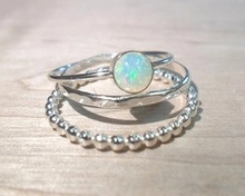 Detailed view of silver minimalist three-piece stacking rings with opal and textured bands