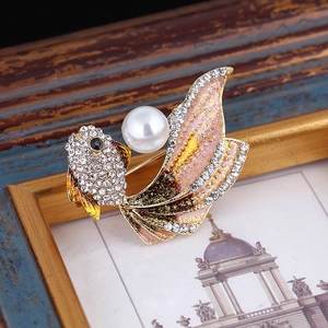 Detail of goldfish brooch with gradient enamel tail and white pearl on vintage background