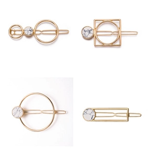 Detail view of golden alloy hair clips with white marble stone in four geometric shapes