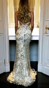 Detail view of champagne gold sequin evening dress featuring a cross back lace-up design