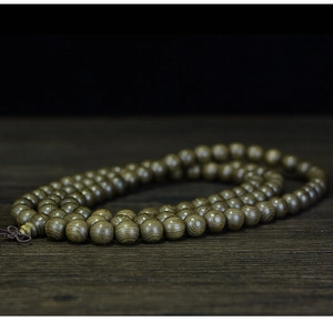 Macro shot of 108 dark wood Buddhist beads with natural grain on a rustic timber base