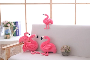 Detailed arrangement of four pink flamingo plush toys in various poses on a grey sofa