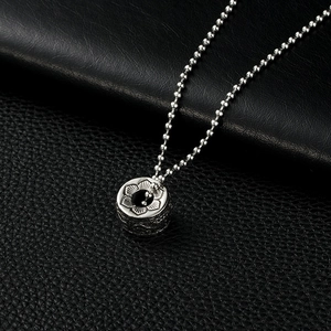 Macro view of silver stainless steel cylinder pendant with detailed lotus relief carving