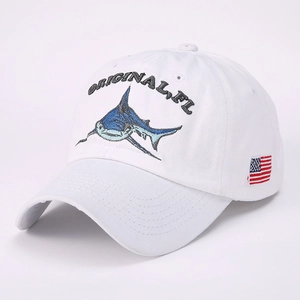 White cotton baseball cap featuring blue shark embroidery and American flag side patch