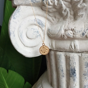 Macro detail of 1953 six pence coin pendant necklace on classic white plaster column