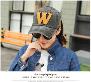 Detail of grey washed denim baseball cap with yellow felt W patch in a street style