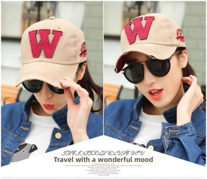Detail of beige cotton baseball cap with red W patch and distressed brim on model
