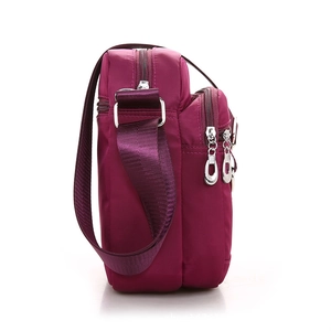 Magenta nylon crossbody bag with multiple zip compartments and adjustable strap
