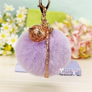 Vue détaillée du porte-clés boule en peluche violette avec cloche dorée et chaînette