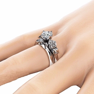 Detailed view of silver rings featuring rose flower designs and a round-cut center stone
