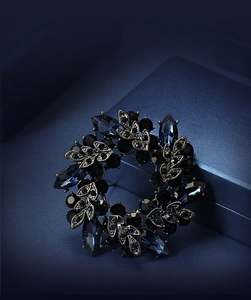 Detailed close-up of a blue crystal floral brooch on a textured luxury gift box