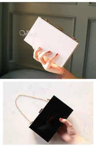 Detail of acrylic box clutch bags in black and white with gold frames and chain straps