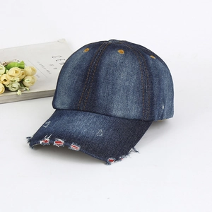 Detail shot of distressed blue denim baseball cap featuring vintage ripped edge texture