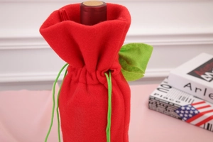 Detail of red felt wine bottle cover with green drawstring and festive leaf ornaments