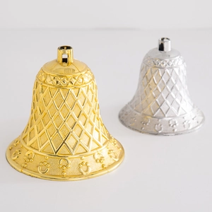 Close-up of gold and silver Christmas plastic bells with diamond grid texture on white background