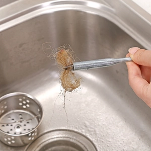 Flexible stainless steel drain clog remover tool grabbing hair debris over a sink