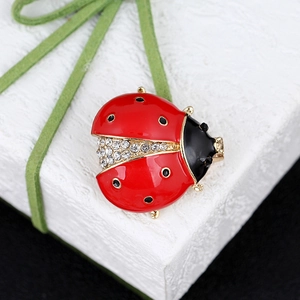Detail of ladybug brooch with red enamel finish and sparkling crystal accents on a gift box